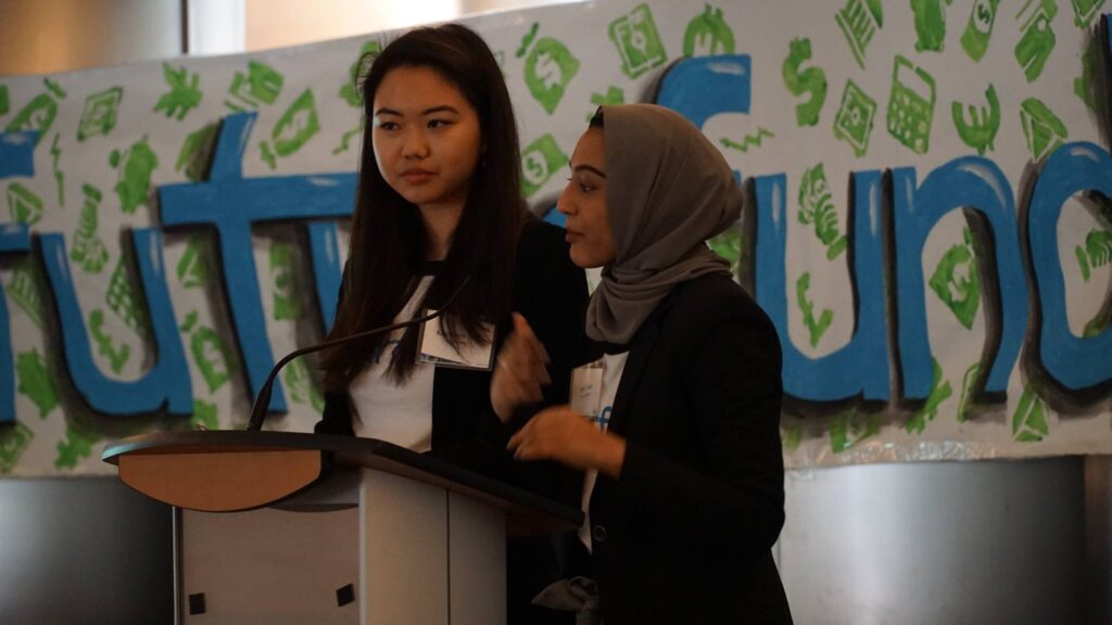 Two women speaking together at a podium for a conference