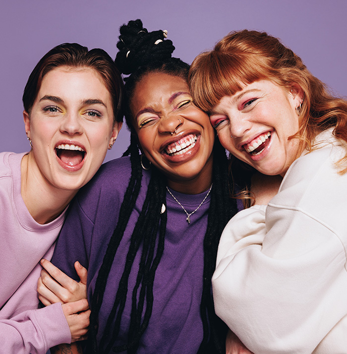 Three women posing for a photo together laughing